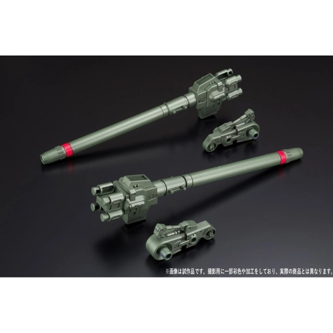  Two green toy cannons with red bands and smaller vehicle attachments on a dark surface.