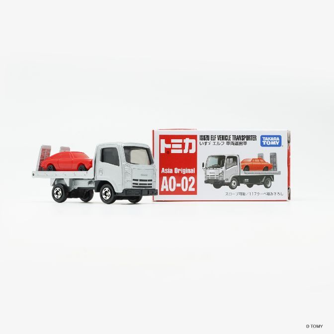  Toy truck with a red car on its flatbed, next to its box.
