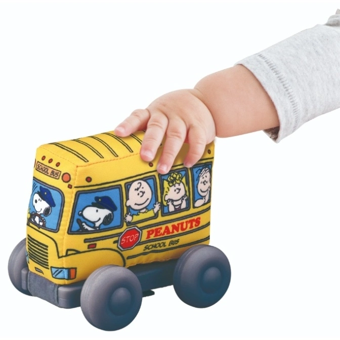  Plush Peanuts school bus toy with Snoopy and friends, being held by a baby's hand.