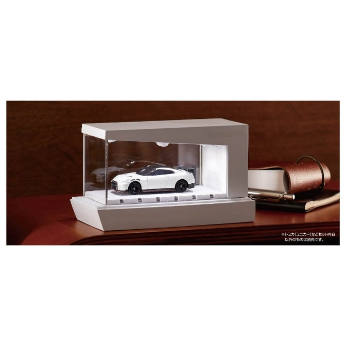  White toy car in a display case on a wooden surface.