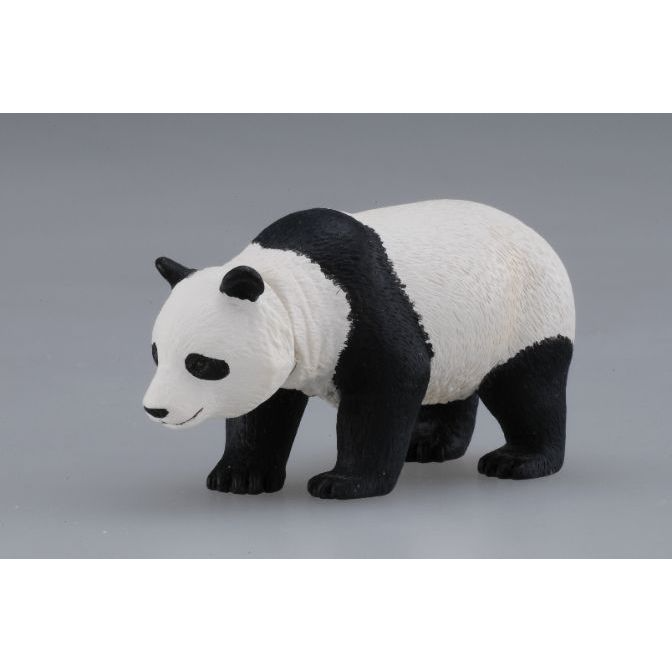 Toy panda bear figurine with black and white fur standing on a gray surface.
