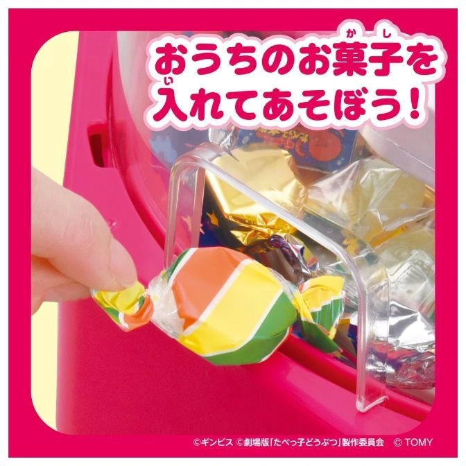  Pink candy dispenser toy with a hand placing a wrapped candy inside.