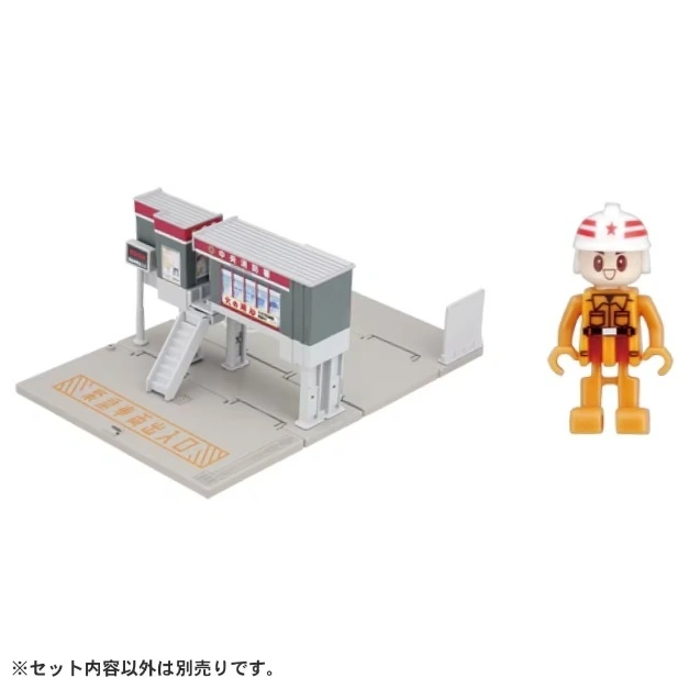  Toy train station with a construction worker figure. The station has stairs and signage.