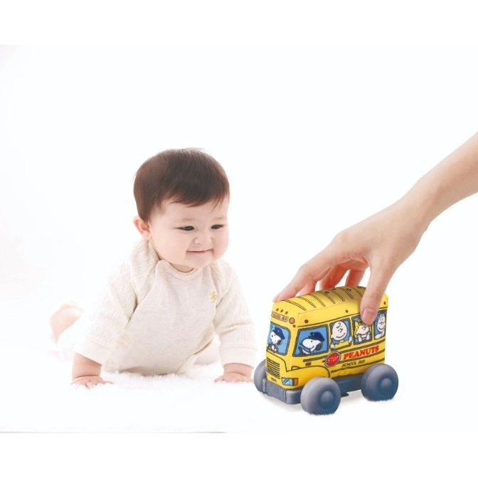  Baby looking at a Peanuts school bus toy being pushed by a hand.