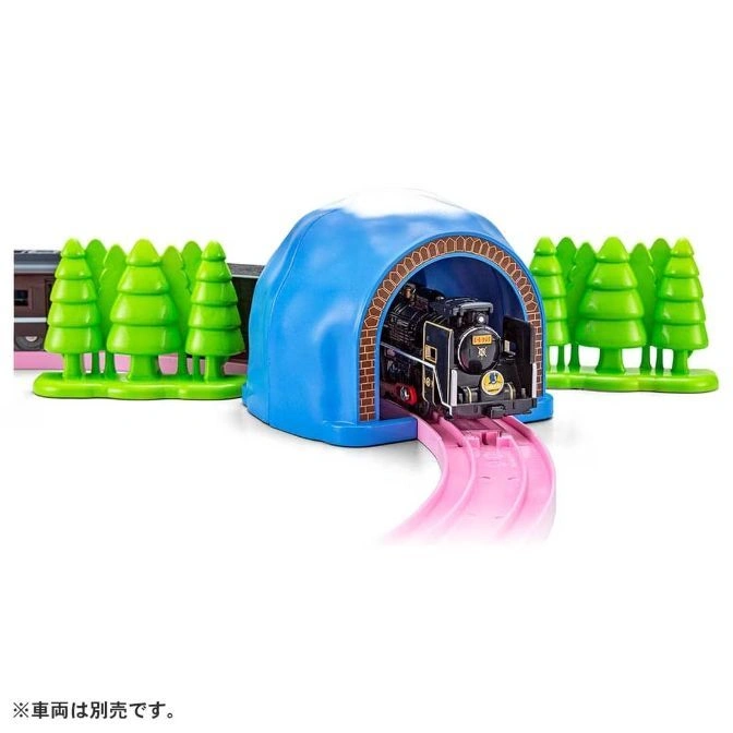  Toy train emerging from a blue tunnel with green trees on either side of a pink track.
