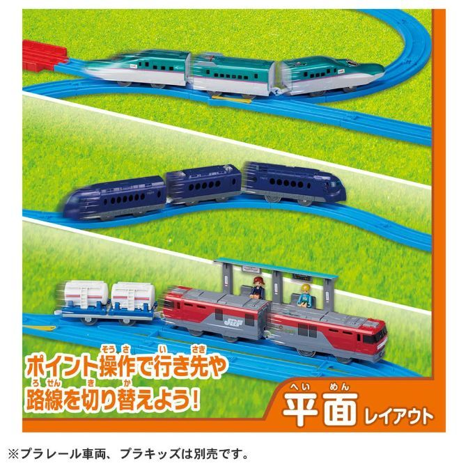  A toy train set with three different trains on blue tracks against a green background.