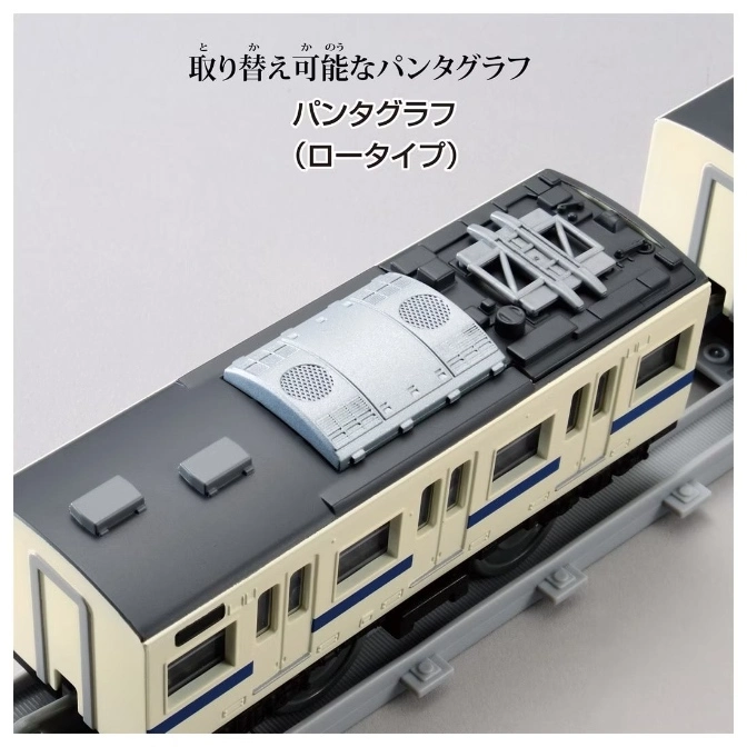  Toy train car with pantograph on a gray track. Cream and dark gray color scheme.