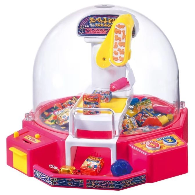 Pink toy crane game with candy prizes inside a clear dome.