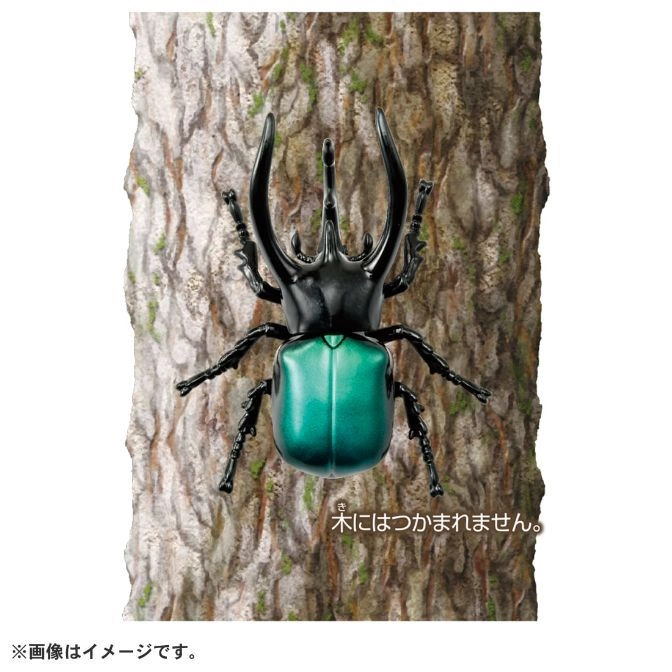  Toy stag beetle with black horns and a green body on a tree trunk.
