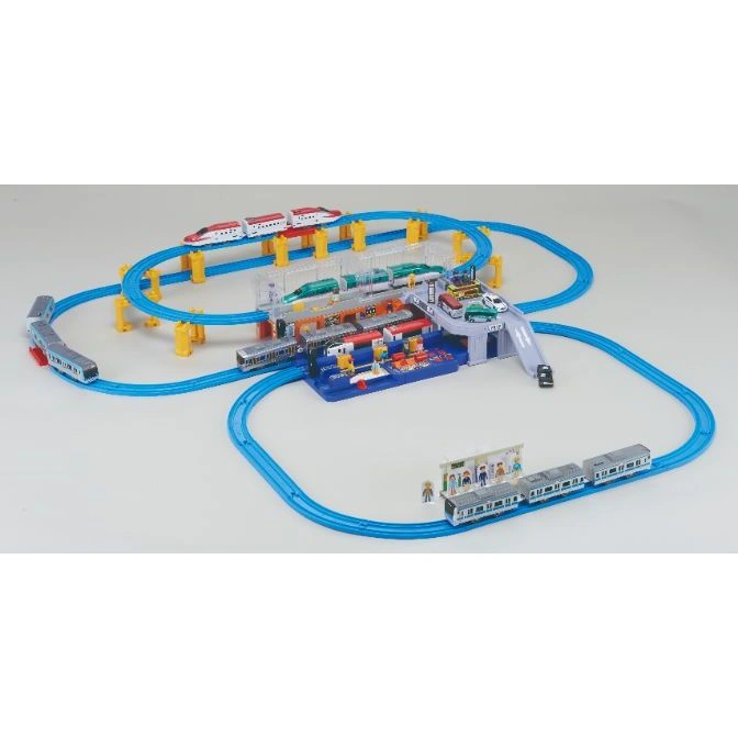  Toy train set with blue tracks, trains, station, and elevated platforms.