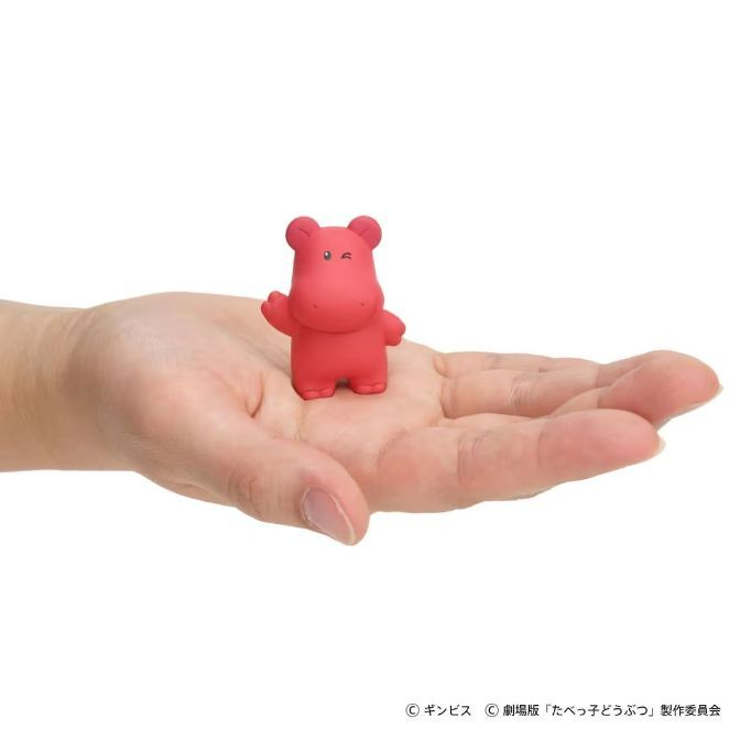 Red hippo toy figure on a hand, waving.