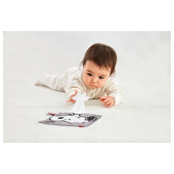  Baby reaching for a Snoopy peek-a-boo toy on a soft white surface.