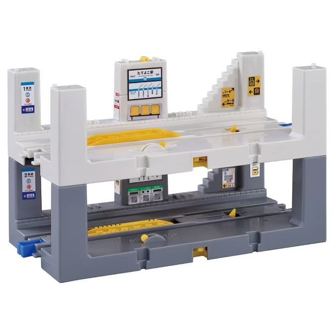 A toy train station with two levels, featuring platforms, tracks, and signage.