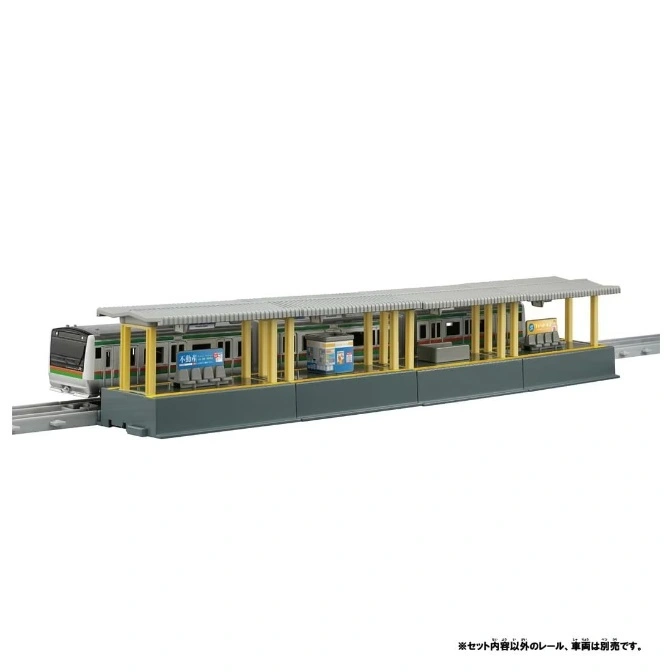  Toy train at station platform with yellow pillars and grey roof, on tracks.