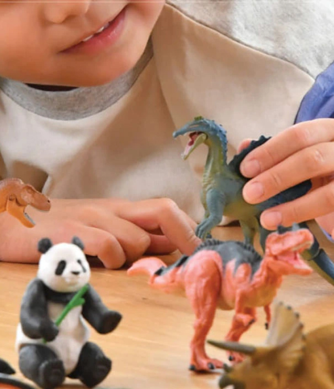 Child playing with ANIA animal and dinosaur figures.