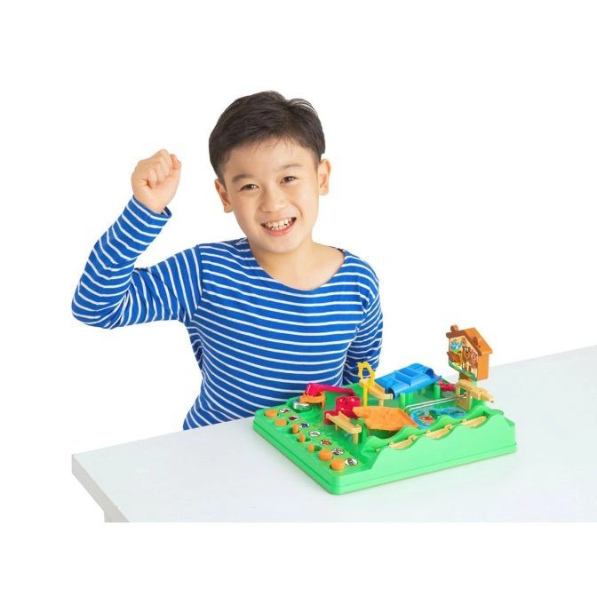  Boy celebrating with a green toy playset featuring a house, slide, and buttons.