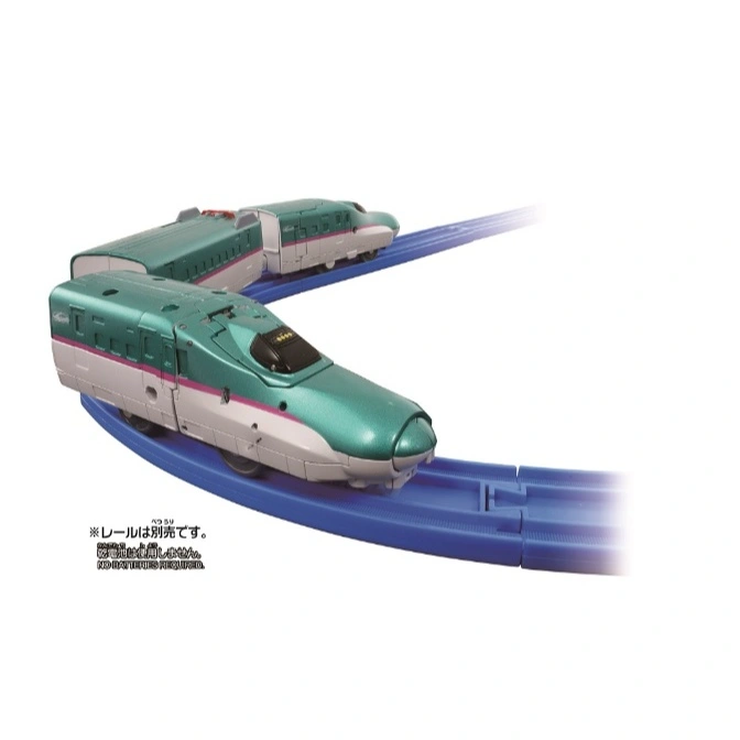  Green toy bullet train on blue tracks. A second train car is visible in the background.