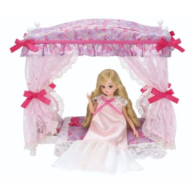 Licca doll in pink nightgown on a canopy bed with pink floral bedding and lace curtains.
