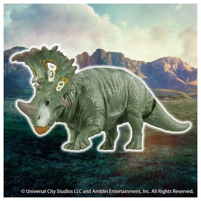  Green Styracosaurus toy with horn and frill, standing on a grassy surface.
