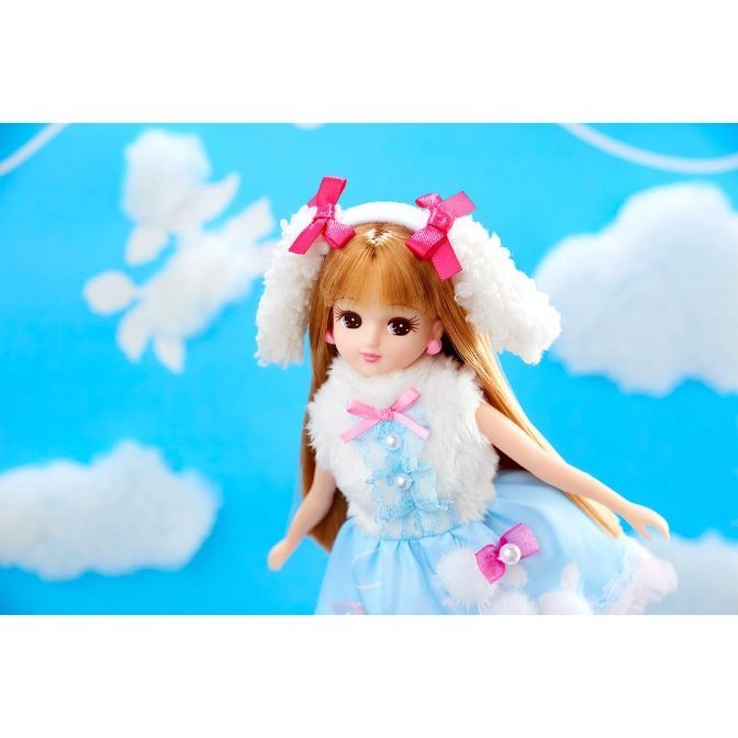  Licca-chan doll in a blue dress with pink bows and fluffy white dog ears against a sky backdrop.