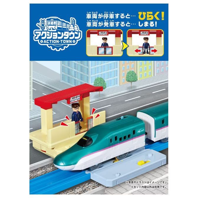 A toy train set with a green and white bullet train, a station with a figure, and a track.