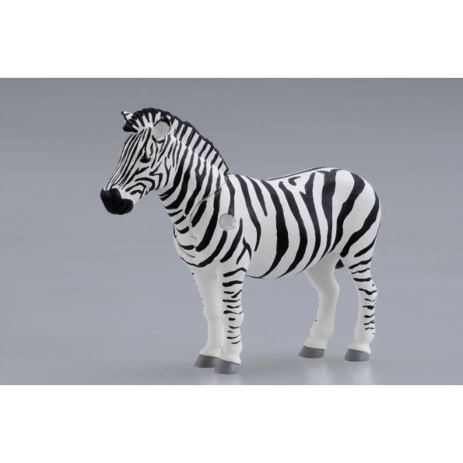 Toy zebra with black and white stripes standing on a gray surface.