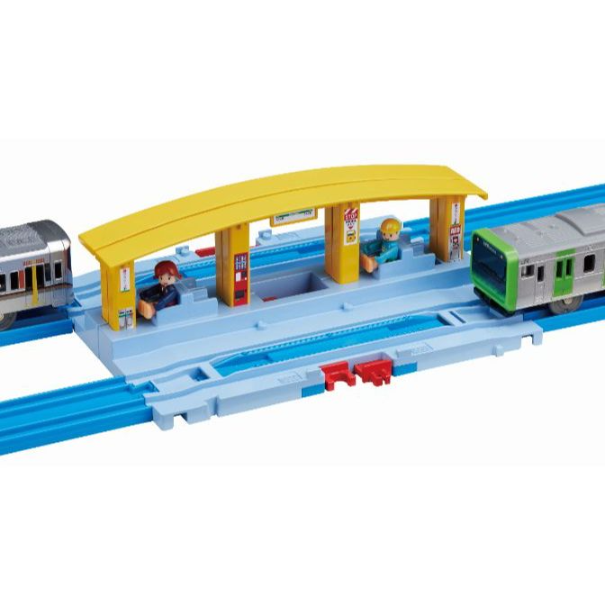  A toy train station with two trains and two figures.