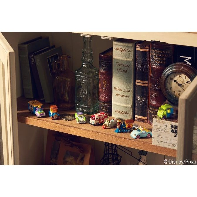  Shelf with toy vehicles, books, bottles, and a clock. The toys are small and colorful.