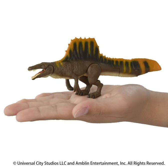  Spinosaurus toy figure with brown body and orange sail on a hand.