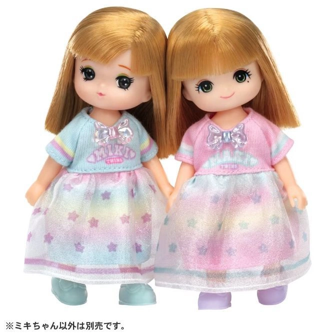  Two blonde dolls in pastel dresses with star patterns, holding hands.