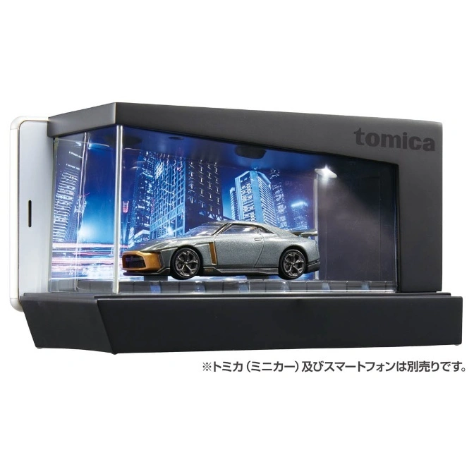 Tomica diecast car in display case with city backdrop and phone attachment.