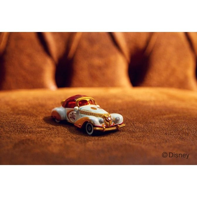  Disney toy car with red roof and white body on brown surface.