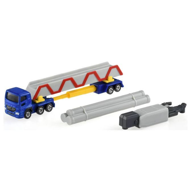  Blue toy truck carrying a gray bridge section, with pipes and a crane arm nearby.