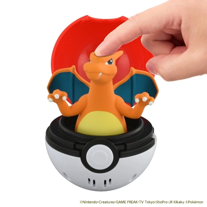 Charizard toy figure popping out of a Poké Ball with a finger pressing its head.