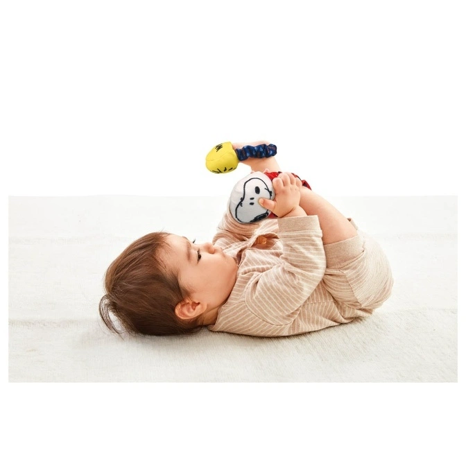  Baby lying down playing with a Snoopy foot finder toy.