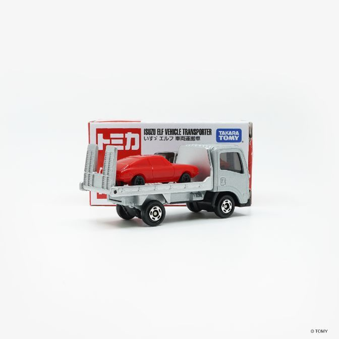  Toy Isuzu truck carrying a red car. The truck has a silver cab and flatbed.