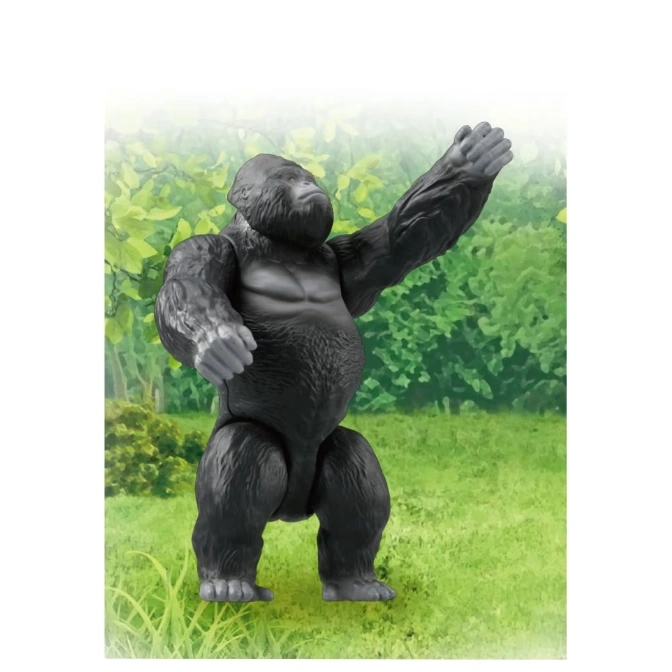  Toy gorilla standing with one arm raised against a grassy, leafy background.