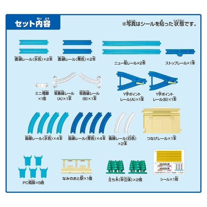  A set of toy train tracks and accessories, including straight and curved tracks in various colors, Y-shaped points, a bridge pier, a station, trees, and stickers.