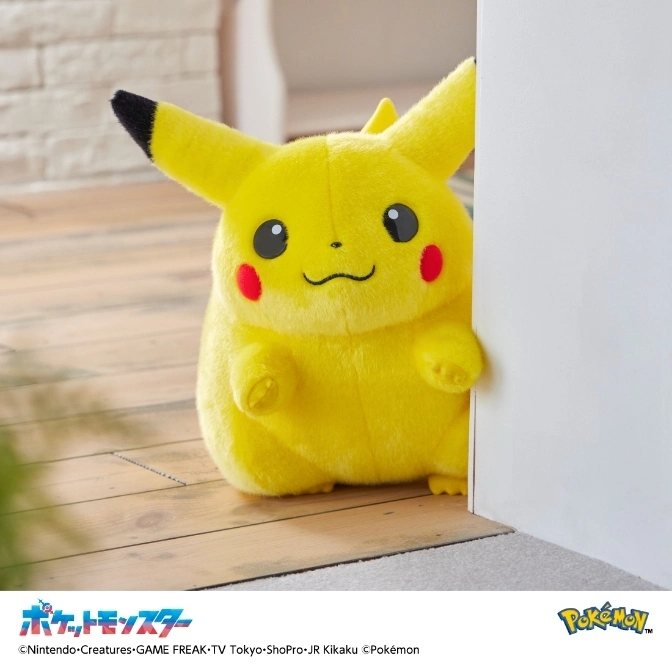  Pikachu plush toy peeking from behind a white wall, with red cheeks and black-tipped ears.
