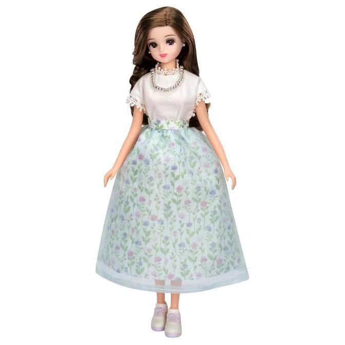 Doll with brown hair, white top, floral skirt, pearl necklace, and sneakers.