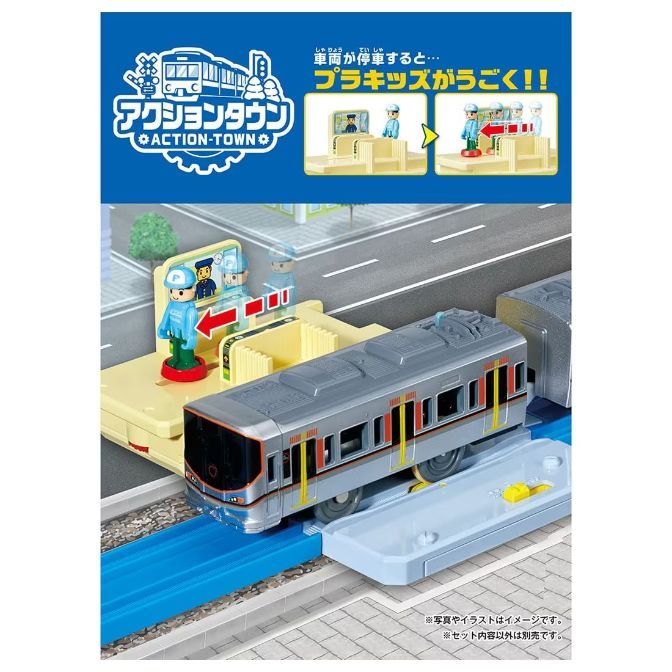  This is a product image of an Action Town toy train set. The set includes a silver train, a station platform with a figure, and blue tracks. The packaging features the Action Town logo and text in Japanese.