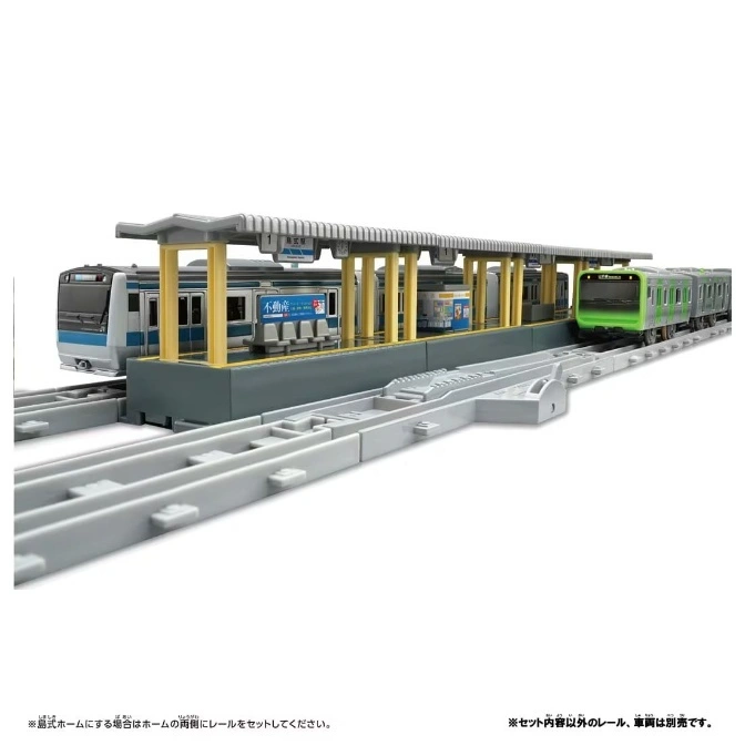  Toy train station with two trains on tracks. One train is blue and white, the other is green.