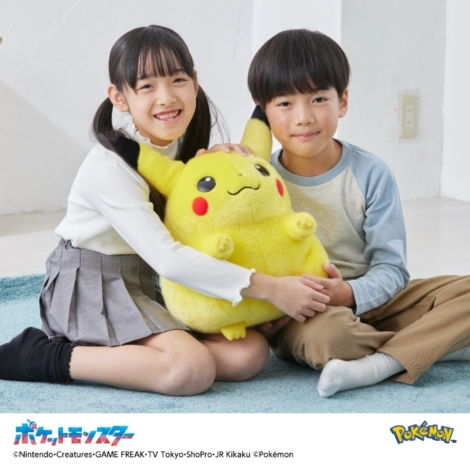  Two kids hugging a large Pikachu plush toy. The toy is yellow with red cheeks and black ears.