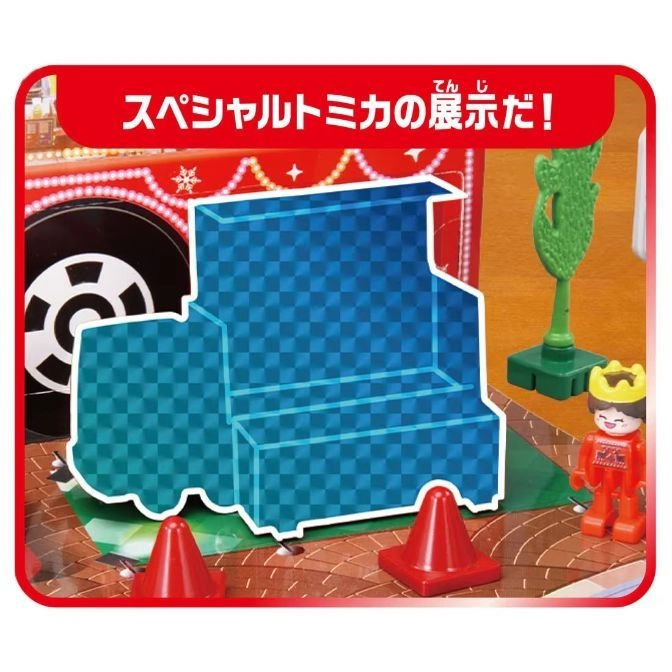  Tomica display set with toy figure, traffic cones, and truck backdrop.