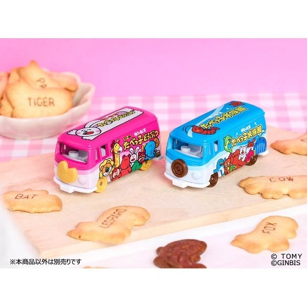  Two animal cracker buses, one pink, one blue, on a wooden board with animal crackers.