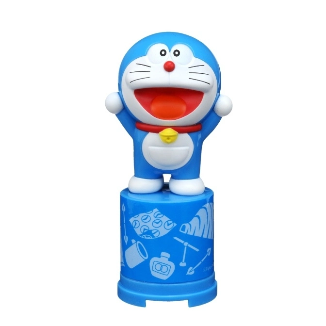  Doraemon toy figure on a blue patterned base, arms raised, smiling.