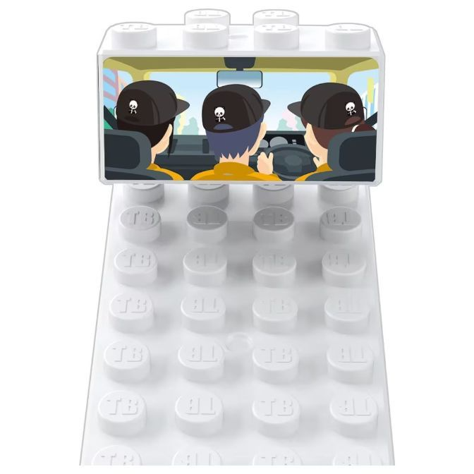  White brick toy with a printed image of three people in a car wearing hats with skull logos.