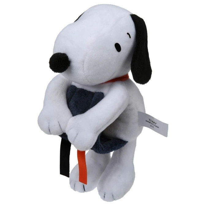 Snoopy plush toy with black ears, nose, and a red collar, holding a black and orange object.