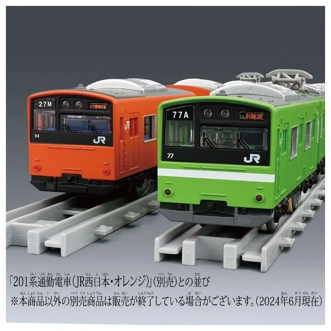  Orange and green toy trains on gray tracks. The orange train has "27M" and the green has "77A".
