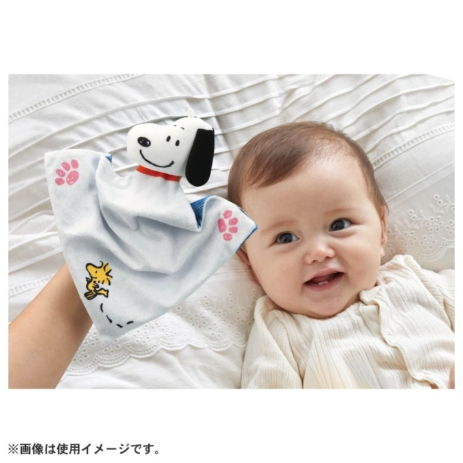  Snoopy hand puppet with paw prints and Woodstock, next to a smiling baby on a white bed.